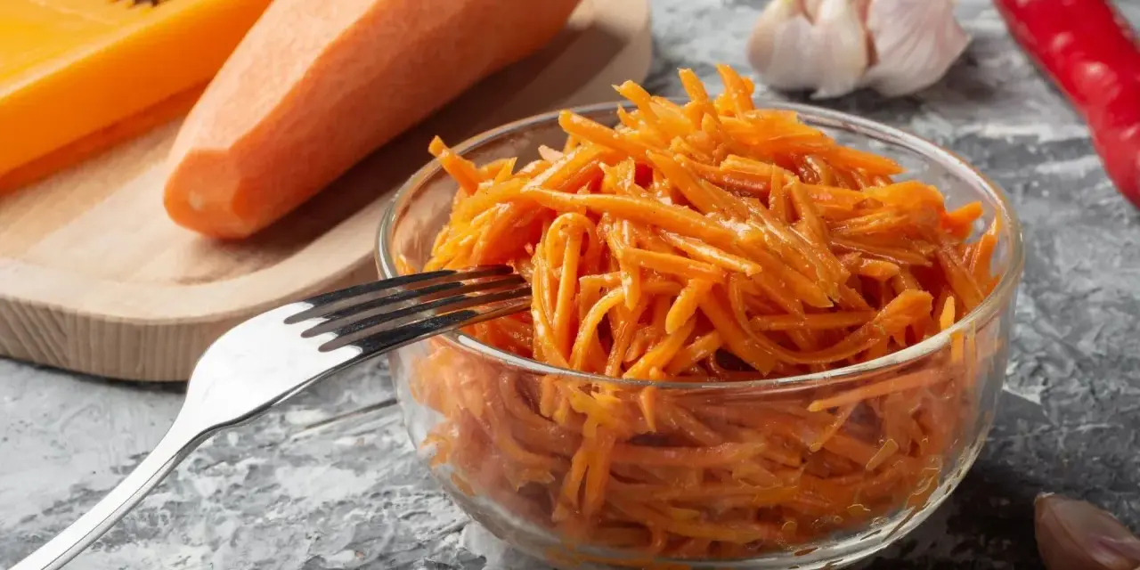 Pyszna surówka z marchewki jak z restauracji, gotowa do podania. Obok marchewka, tarka, czosnek i papryczka chili.