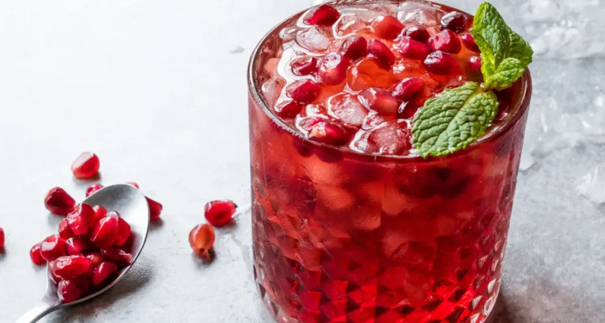 Orzeźwiający drink z grenadyną i rumem, ozdobiony świeżymi pestkami granatu i miętą. Idealny na letnie wieczory.