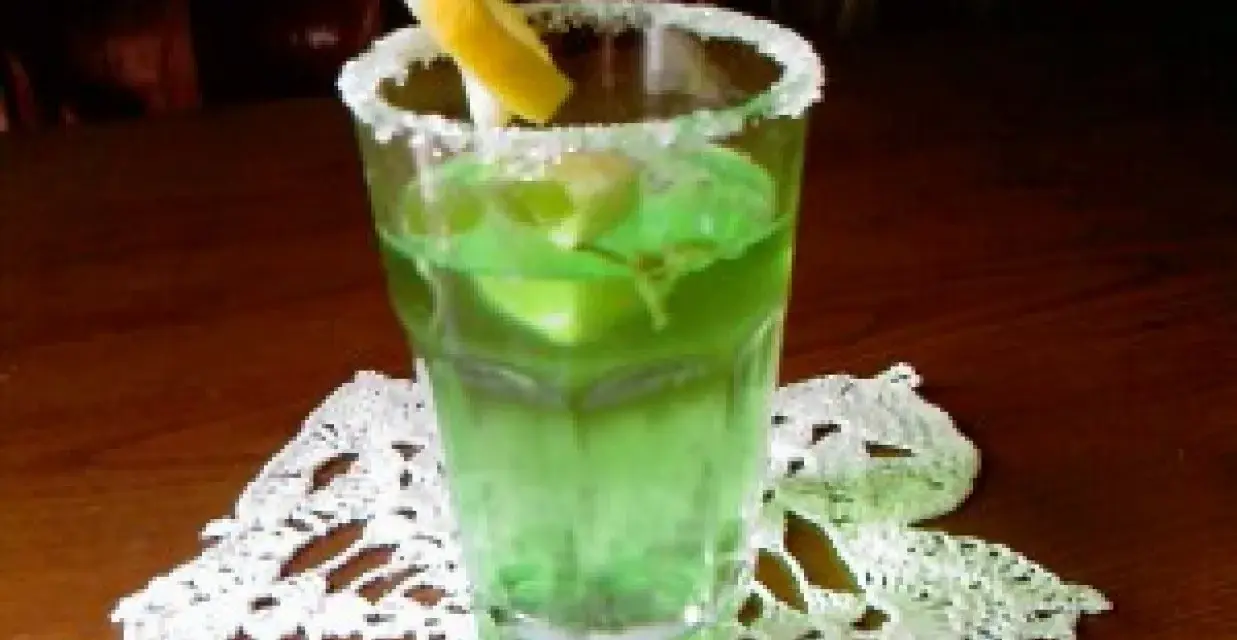 Orzeźwiający drink z likierem miętowym, lodem i plasterkiem cytryny, ozdobiony cukrowym rantem.