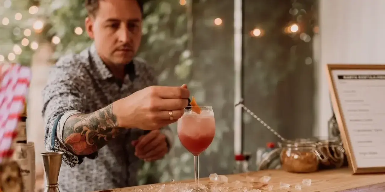 Barman z tatuażem na ręce przygotowuje drinka na 18. urodziny. Zastanawiasz się, ile kosztuje barman na 18?