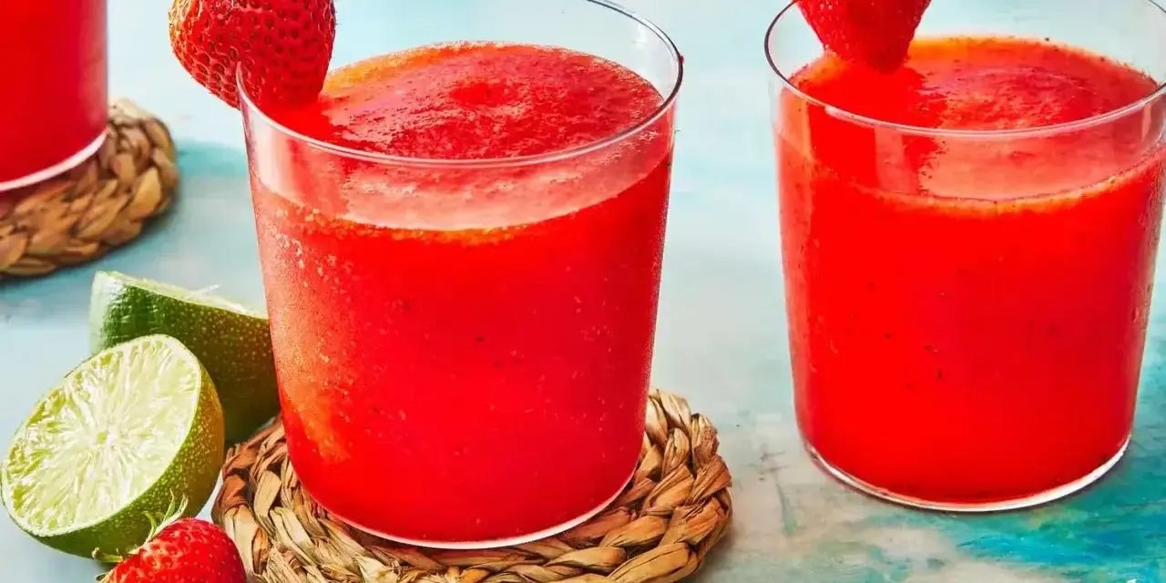 Orzeźwiający drink z truskawkami, ozdobiony świeżymi owocami i limonką, idealny na upalne dni.