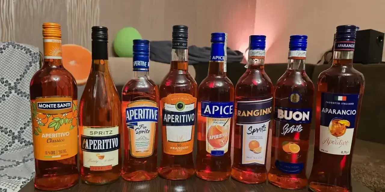 Pimm’s No. 1 kontra Aperol Spritz: rząd butelek włoskich aperitifów, głównie pomarańczowych, gotowych na imprezę.