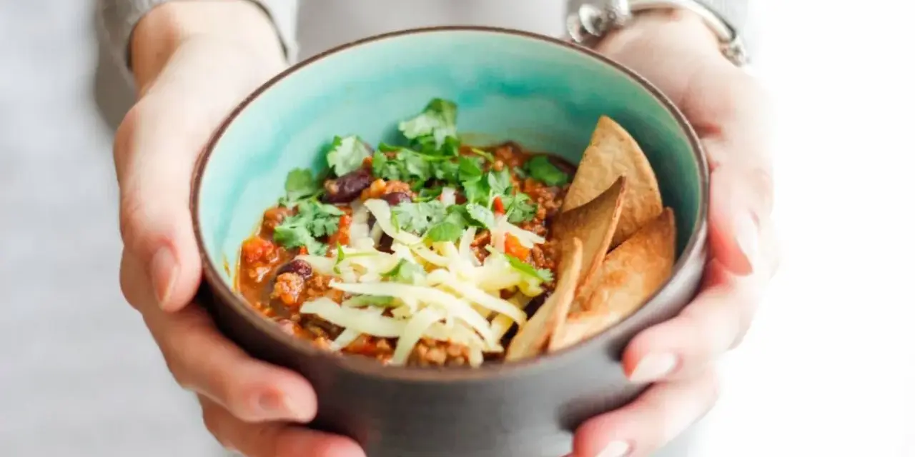 Miseczka pysznego chili con carne przepis, posypana serem i świeżą kolendrą, z chrupiącymi nachos. Idealne na chłodne dni.