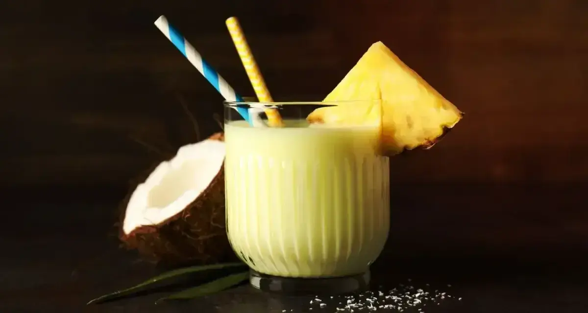 Orzeźwiający drink z mlekiem, kokosem i ananasem, ozdobiony plasterkiem owocu i kolorowymi słomkami. Idealny na tropikalne popołudnie.