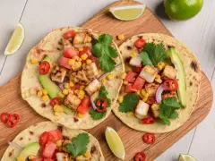 Zdrowy obiad dietetyczny: tortille z grillowanym tofu, kukurydzą, pomidorami, awokado i kolendrą.