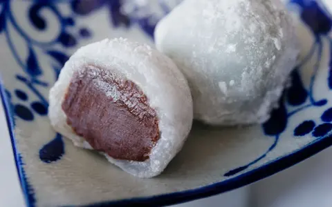 Pyszne mochi z czekoladowym nadzieniem, posypane cukrem pudrem. Idealne do domowego przepisu na mochi.