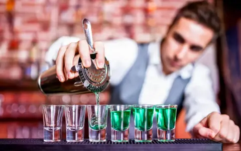 Barman nalewa zielony shot. Chcesz wiedzieć, jak zostać barmanem? To pierwszy krok do mistrzostwa!