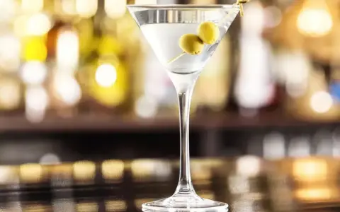 Klasyczny martini dry przepis: schłodzony gin, odrobina wermutu i dwie oliwki. Idealny drink na wieczór.