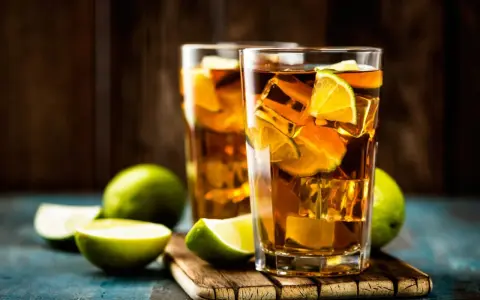 Dwa orzeźwiające drinki: Long Island Iced Tea czy Tokyo Tea, z lodem i limonką, na drewnianej desce.