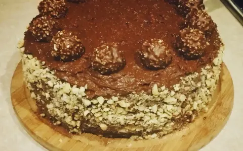 Czekoladowy tort udekorowany chrupiącymi orzechami i pysznymi pralinami Ferrero Rocher.