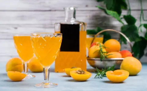 Orzeźwiający drink z likierem brzoskwiniowym, podany w eleganckich kieliszkach, z owocami i butelką w tle.