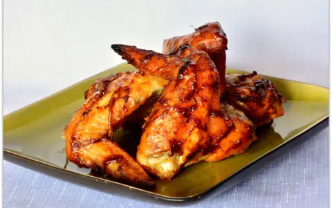 Skrzydełka z BBQ lśniące od sosu, obok udka z kurczaka w ziołach. Pyszna uczta!