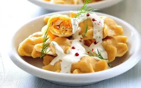 Pyszne pierogi z farszem, polane sosem i posypane koperkiem. Idealne co na obiad dla gości, by ich zachwycić.