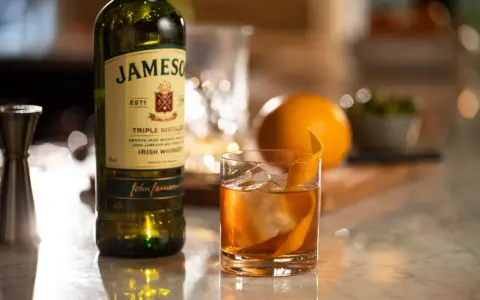 Old Fashioned na bourbonie czy na żytniej whisky? Jameson Irish Whiskey obok drinka z pomarańczą i lodem.