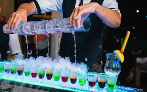 Barman nalewa kolorowe shoty na weselu. Zastanawiasz się, ile bierze barman na weselu za taką atrakcję?