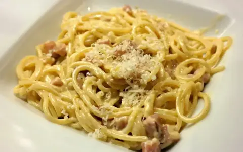 Pyszne spaghetti carbonara ze śmietaną, posypane parmezanem. Idealne na szybki obiad.