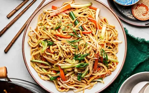 Pyszny makaron chow mein z warzywami i sezamem, gotowy do jedzenia pałeczkami.