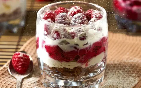 Pyszny deser w pucharku z malinami i kremem, posypany cukrem pudrem. Lepszy niż ciasto na wagę!