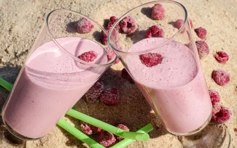 Dwa pyszne, różowe drinki z jajkiem i malinami na piasku. Idealne na letnie orzeźwienie.