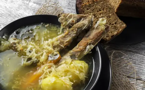 Kapuśniak ze świeżej kapusty czy kwaśnica? Aromatyczna zupa z żeberkami, ziemniakami i kiszoną kapustą, podana z ciemnym chlebem.