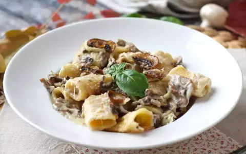 Pyszne spaghetti z grzybami w kremowym sosie, udekorowane listkiem bazylii. Idealne na jesienny obiad.