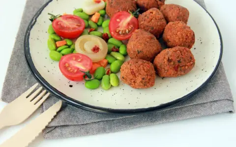 Falafel kontra kotlety sojowe: chrupiące kulki falafela i soczyste pomidorki z edamame na talerzu.