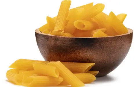 Makaron bezglutenowy kukurydziany w drewnianej misce, obok garść makaronu. Ryżowy też jest pyszny!