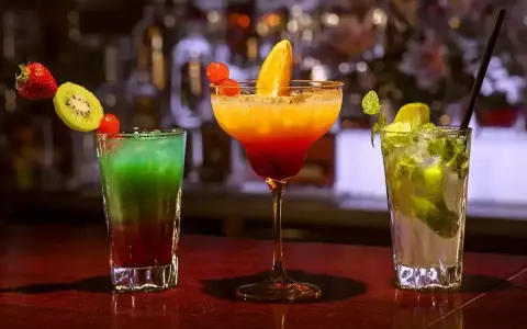 Kolorowe drinki przepisy: zielony, pomarańczowo-czerwony i zielony z miętą, ozdobione owocami. Idealne na letnie wieczory.