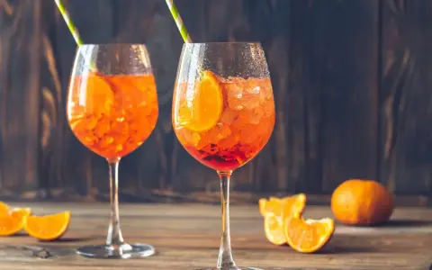 Dwa orzeźwiające drinki z sokiem pomarańczowym, lodem i plasterkiem pomarańczy, ozdobione słomkami.
