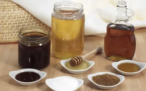 Domowy syrop cukrowy i kupny syrop barmański obok miodu i cukru.