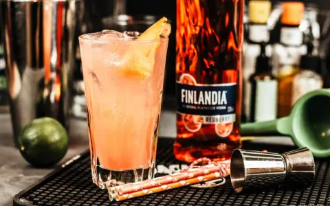 Orzeźwiające drinki z Finlandia Redberry, idealne na letnie wieczory. W szklance różowy koktajl z lodem i skórką cytrusową.