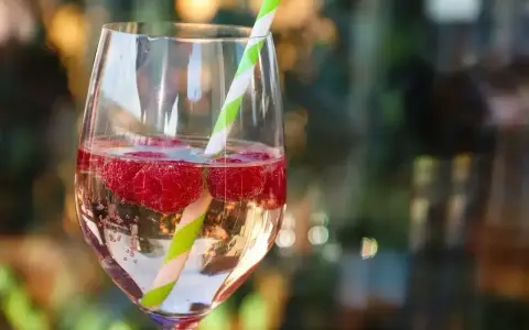 Orzeźwiający drink z bacardi malinowym, z bąbelkami i malinami, ozdobiony słomką.