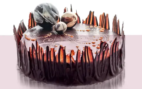 Elegancki tort czekoladowy ozdobiony czekoladowymi piórami i marmurkowymi kulami. Inspiracja, jak ozdobić tort czekoladowy.
