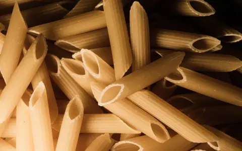Stos makaronu penne, czy to orkiszowy czy żytni, czeka na gotowanie.