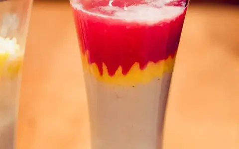 Warstwowy drink z sokiem bananowym, truskawkami i czymś żółtym. Wygląda pysznie!