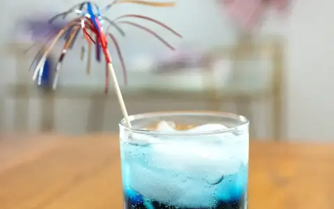 Niebieski drink z lodem i parasolką, przypominający letni koktajl z blue curacao.