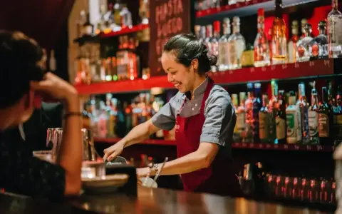 Uśmiechnięta barmanka przygotowuje drinki za ladą pełną alkoholi. Ciekawe, ile zarabia barman w Turcji?