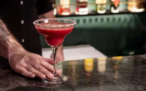 Margarita klasyczna kontra Margarita truskawkowa. Barman podaje orzeźwiającą, mrożoną truskawkową Margaritę z solą na brzegu kieliszka.