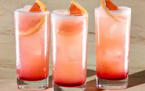 Trzy orzeźwiające drinki: Tequila Sunrise i Paloma, z plasterkami grejpfruta i lodem.