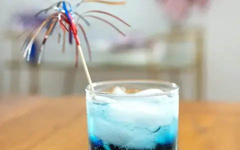 Orzeźwiający drink z grenadyną i blue curacao, ozdobiony kolorową parasolką, idealny na letnie popołudnie.