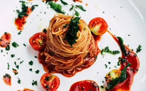 Eleganckie spaghetti bez mięsa, podane z sosem pomidorowym, świeżymi pomidorkami koktajlowymi i posypane ziołami.
