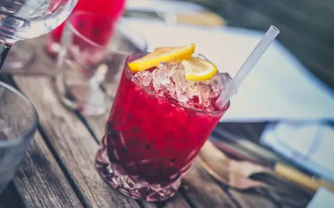 Orzeźwiające drinki z wódką dla pań, z lodem i plasterkami cytryny, na drewnianym stole.