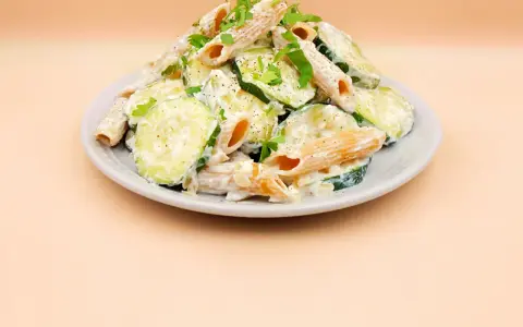 Makaron z cukinii przepis: penne w kremowym sosie z plasterkami cukinii, posypane natką pietruszki i pieprzem.