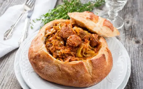 Bigos staropolski w chlebie, sycące danie z kapusty i kiełbasy, idealne na zimowe wieczory.
