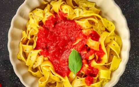 Pappardelle czy fettuccine? Szeroki makaron z sosem pomidorowym i listkiem bazylii, wygląda pysznie!