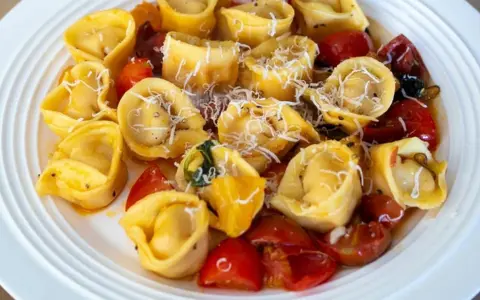 Pyszne tortellini z pomidorkami i parmezanem na białym talerzu. Idealne danie, czy ravioli czy tortellini?
