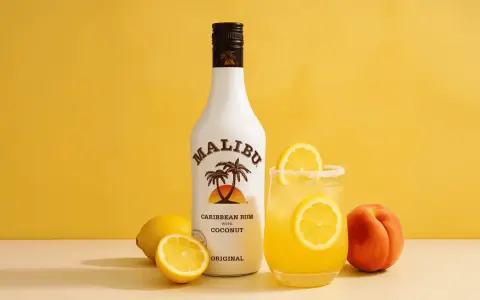 Orzeźwiający drink z malibu przepis: kokosowy rum, cytryny i brzoskwinia na żółtym tle. Idealny na lato!