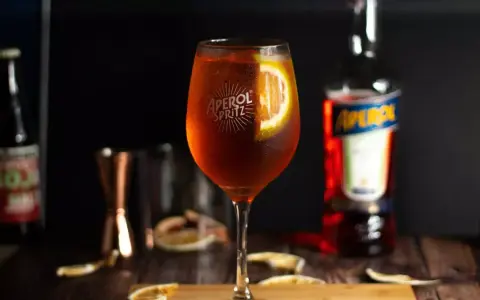 Orzeźwiający drink z aperolem i wódką, ozdobiony plasterkiem pomarańczy. Idealny na letnie wieczory.