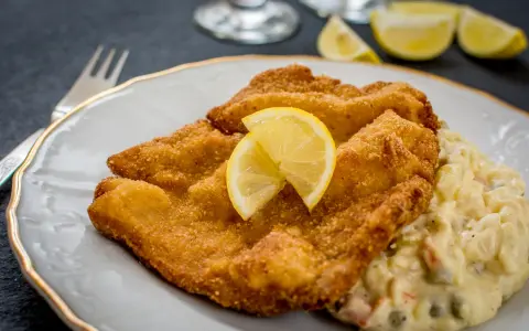 Złocisty sznycel cielęcy i kotlet schabowy, podane z cytryną i sałatką jarzynową. Pyszny obiad!