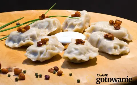Pyszne pierogi ruskie kontra pierogi z mięsem, podane na desce z chrupiącym skwarkami i śmietaną.